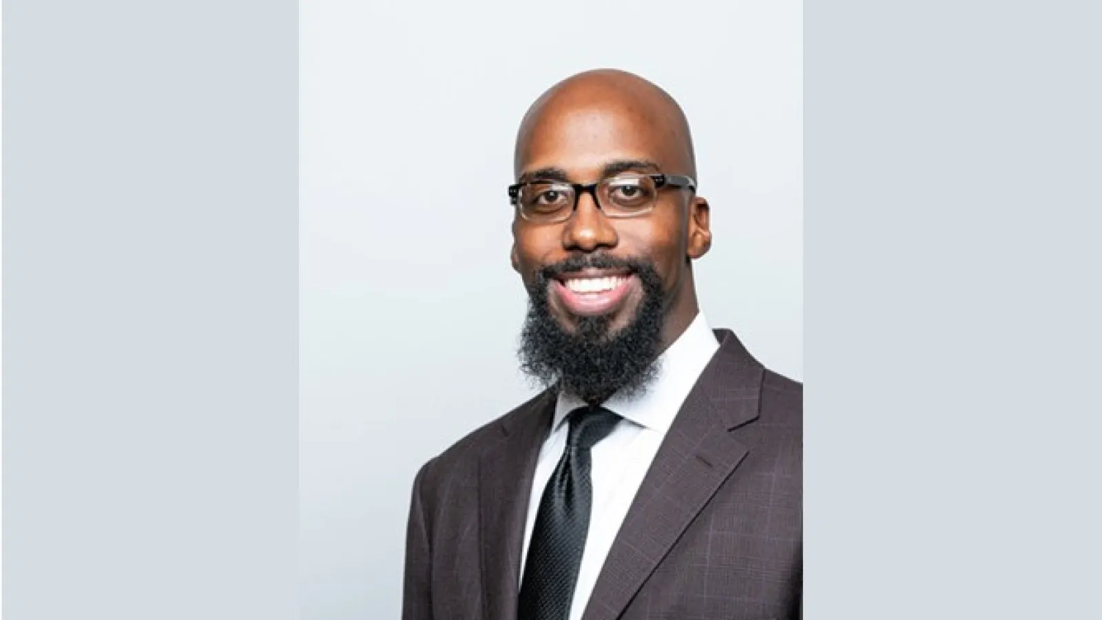 Dr. Seth Gaiters with dark grey suit and black glasses