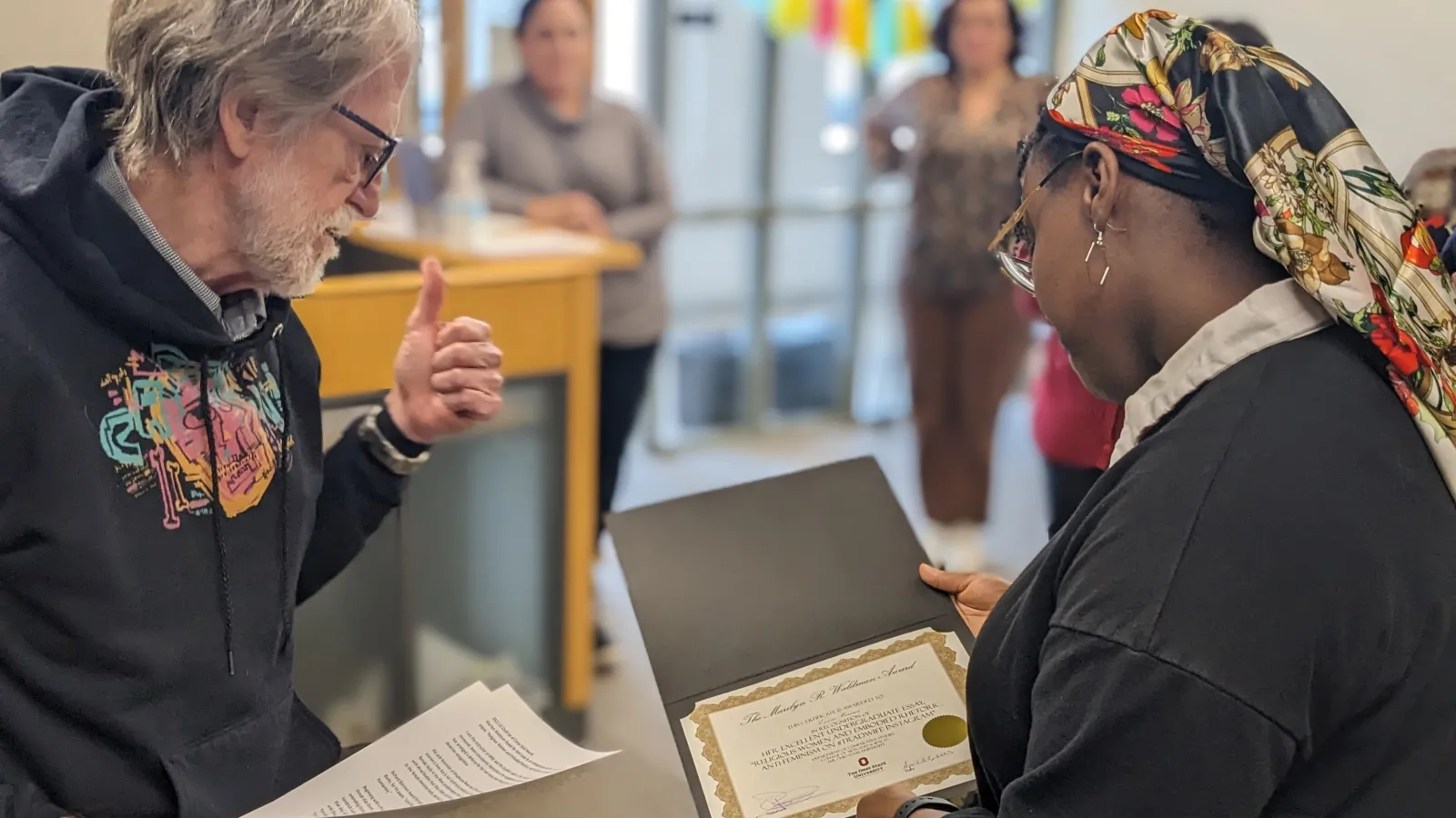 Dr. Barry Shank hands an award to Emoni