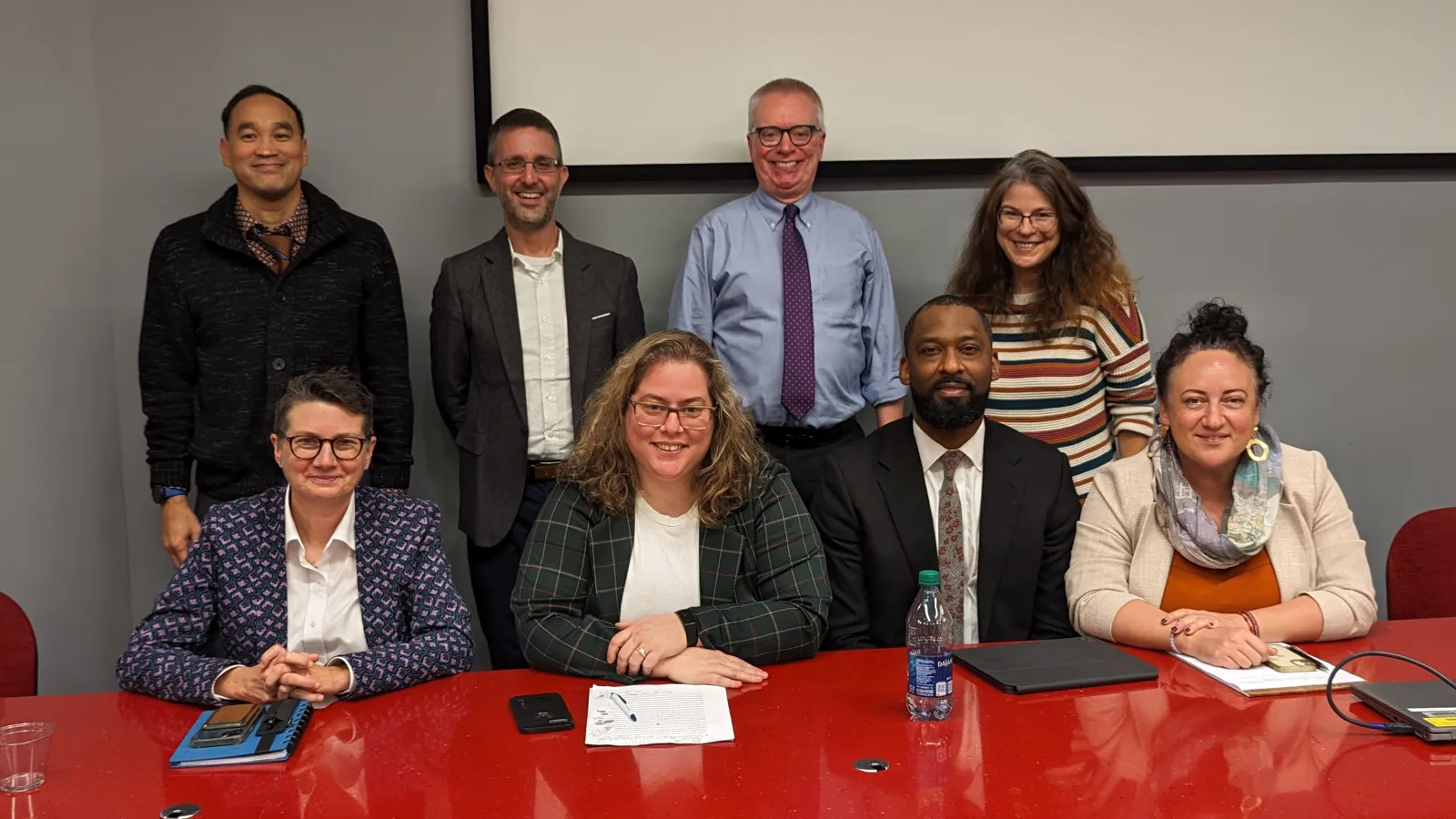 Davis Colloquium organizers and panelists sitting behind a red table