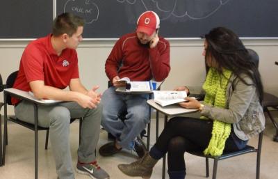 Three students having a discussion in a classroom