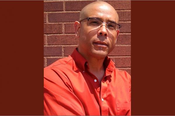 Individual wearing glasses and reddish orange shirt