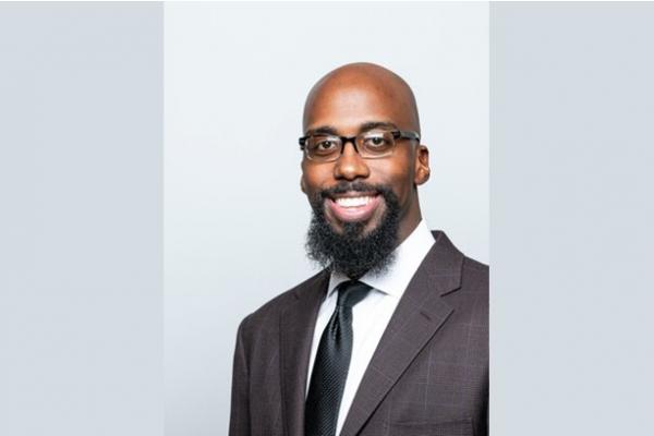 Dr. Seth Gaiters with dark grey suit and black glasses