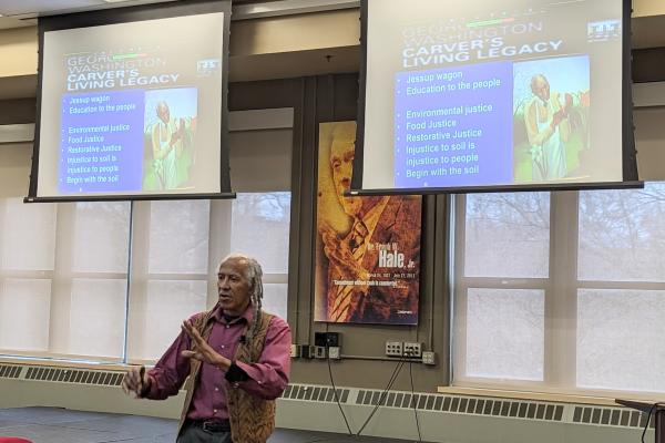 Jim Embry speaking with image of George Washington Carver on projector screen