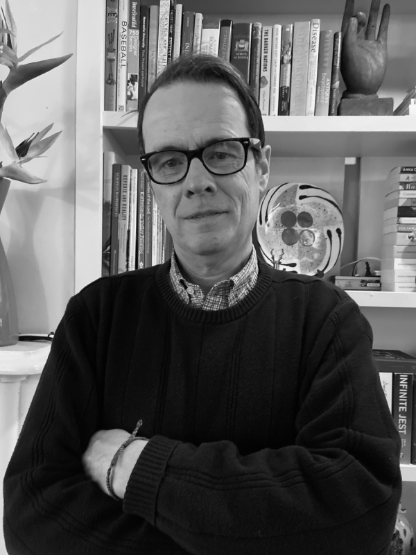 Black and white photo of Greg, with glasses and a dark sweater