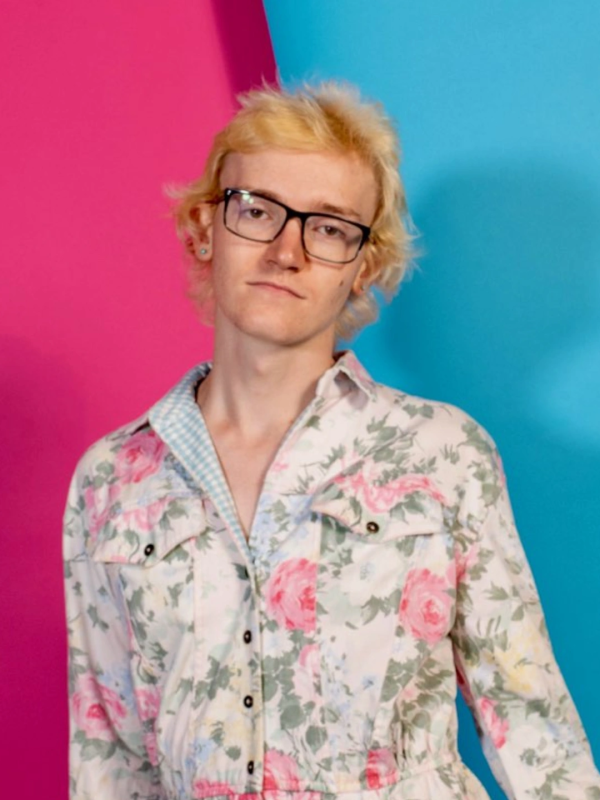 Penelope standing in front of a pink and blue background.