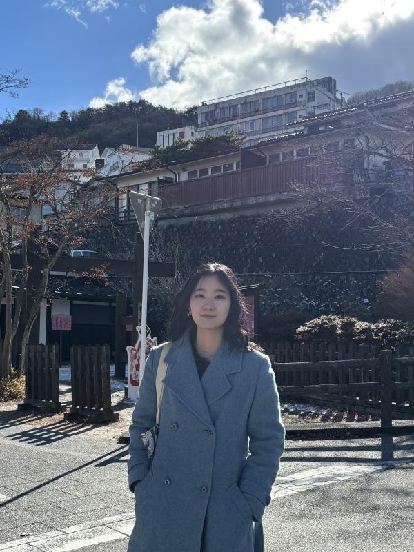 A picture of a woman standing in front of a building 