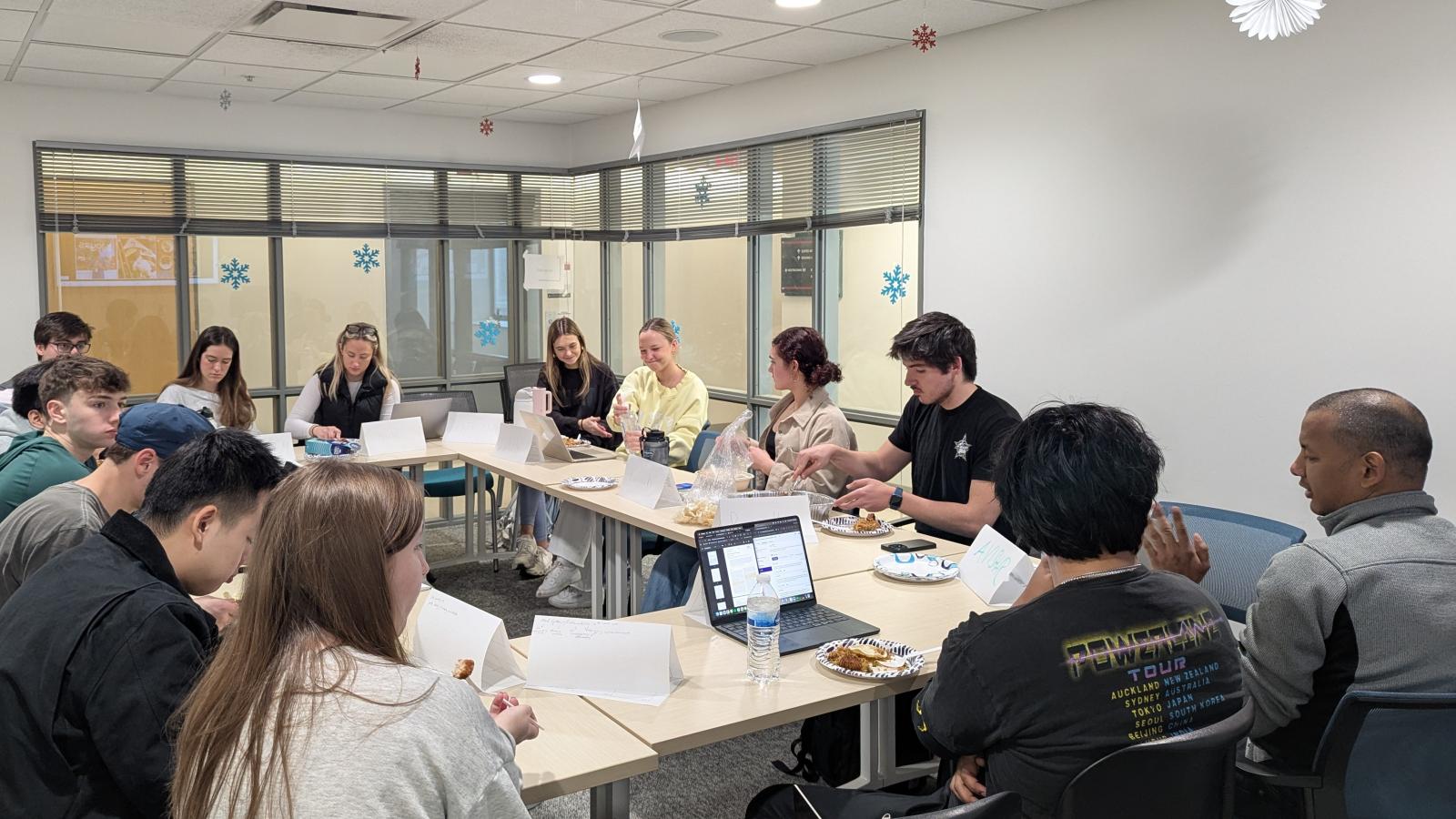 Students sitting around tables with Chef Avishar in bottom right corner of image
