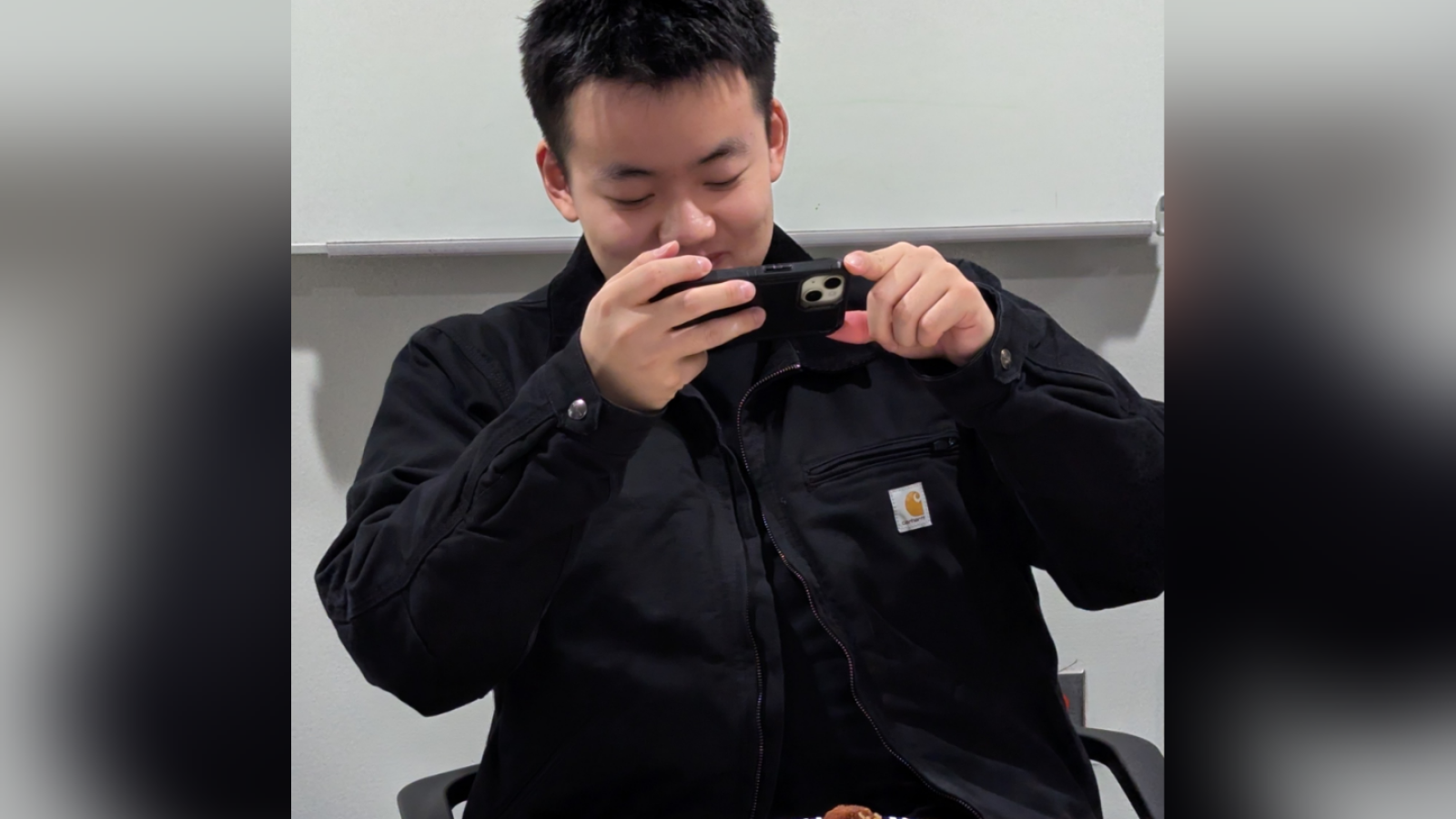 Student in black jacket taking a photo of food sample